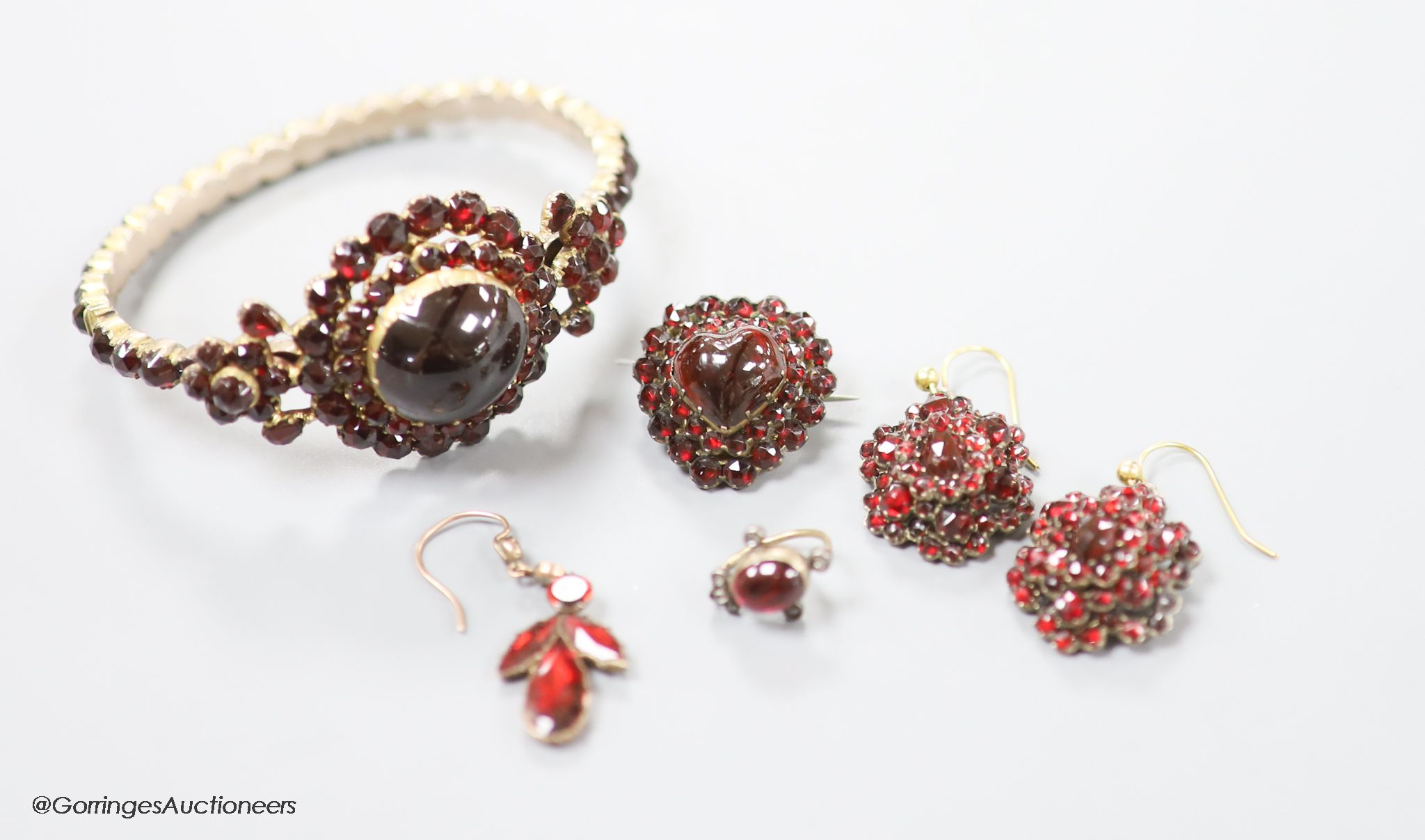 A Victorian gilt metal, facet and cabochon cut garnet set hinged bracelet, a pair of similar earrings and three other garnet set items.